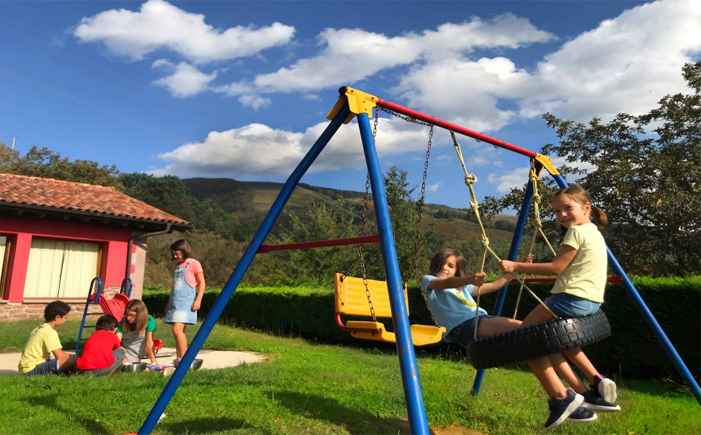 Group of children playing in the garden of a rural house.